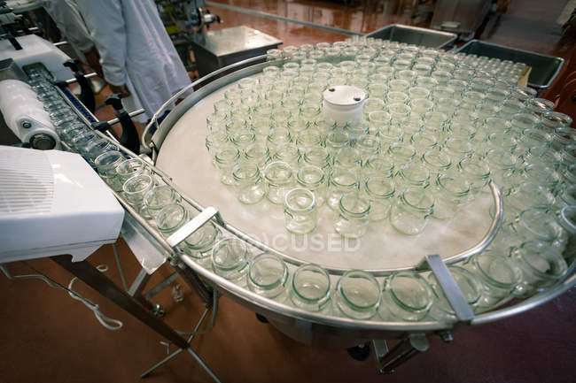 Frascos de vidrio vacíos en la línea de producción en la fábrica de alimentos - foto de stock