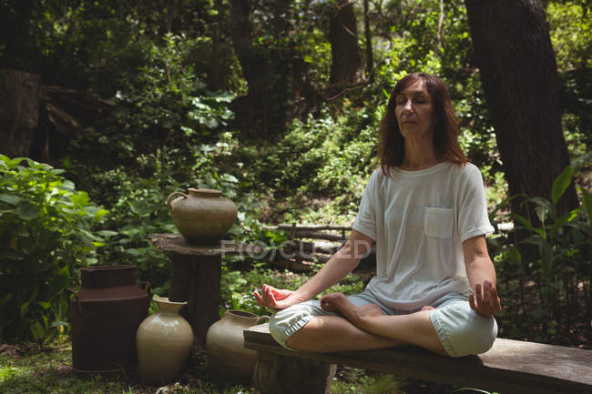 Femme pratiquant le yoga dans le jardin par une journée ensoleillée — Photo de stock