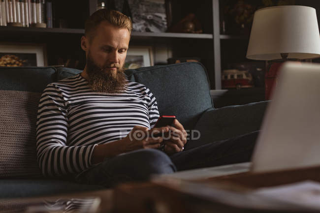 Mann sitzt mit Handy zu Hause auf Sofa — Stockfoto