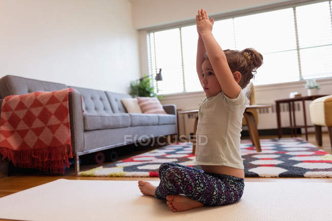 Linda chica realizando yoga en la sala de estar en casa - foto de stock