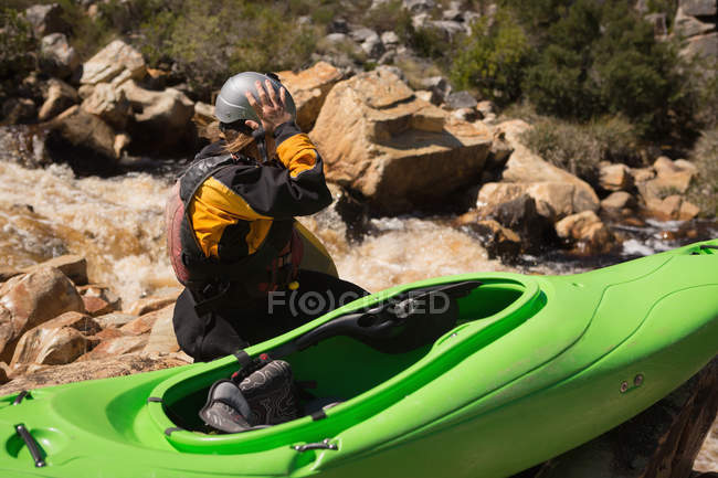 Donna seduta con barca kayak su rocce lungo il fiume . — Foto stock