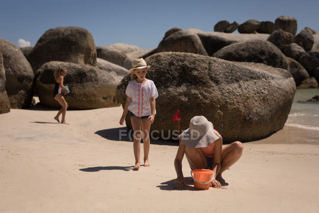 Famille jouant dans le sable à la plage par une journée ensoleillée — Photo de stock