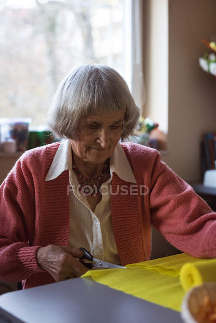 Senior woman cutting crepe paper in nursing room — Stock Photo