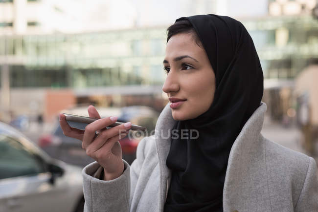 Женщина в хиджабе разговаривает по мобильному телефону на городской улице — стоковое фото