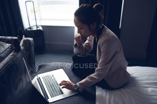Woman using laptop on bed in hotel — Stock Photo
