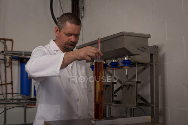 Travailleur masculin vérifiant la qualité du gin dans l'usine — Photo de stock