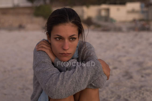 Woman sitting in beach at dusk. — Stock Photo