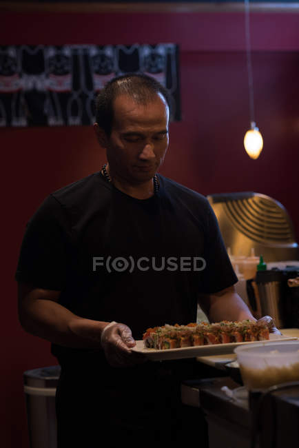 Koch trägt Sushi in einem Tablett, um es in einem Restaurant zu servieren — Stockfoto