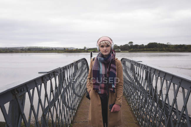 Porträt einer Frau in warmer Kleidung, die auf einer Brücke steht — Stockfoto
