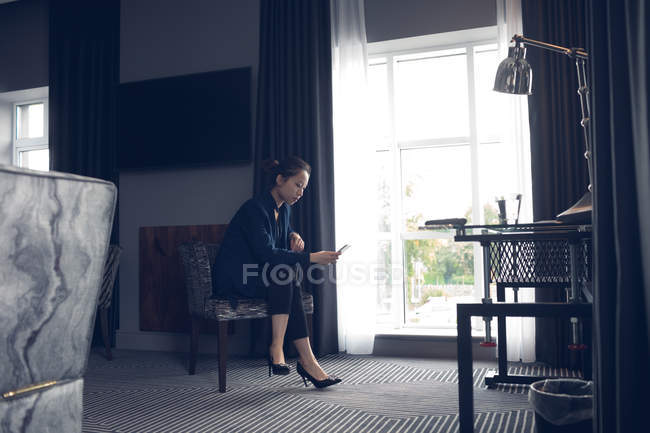 Женщина с помощью мобильного телефона в номере отеля — стоковое фото