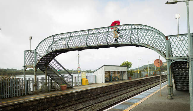 Жінка йде з парасолькою на мосту на вокзалі — стокове фото
