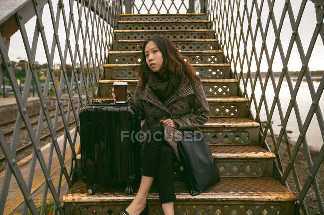 Mulher pensativa sentada na escadaria na estação ferroviária — Fotografia de Stock