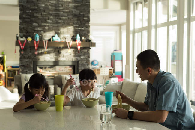 Hijas desayunando con su padre en casa - foto de stock