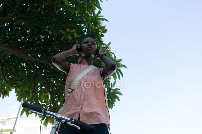 Mulher usando fones de ouvido na rua da cidade em um dia ensolarado — Fotografia de Stock