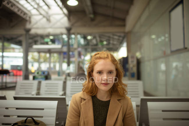 Porträt einer jungen Frau mit roten Haaren, die an einer Bushaltestelle auf den Bus wartet — Stockfoto