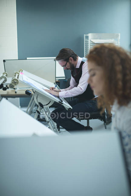 Male executive working over drafting table in office — Stock Photo