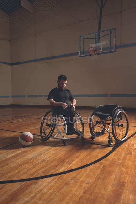 Hombre discapacitado ajustando cinturón de silla de ruedas en la corte - foto de stock