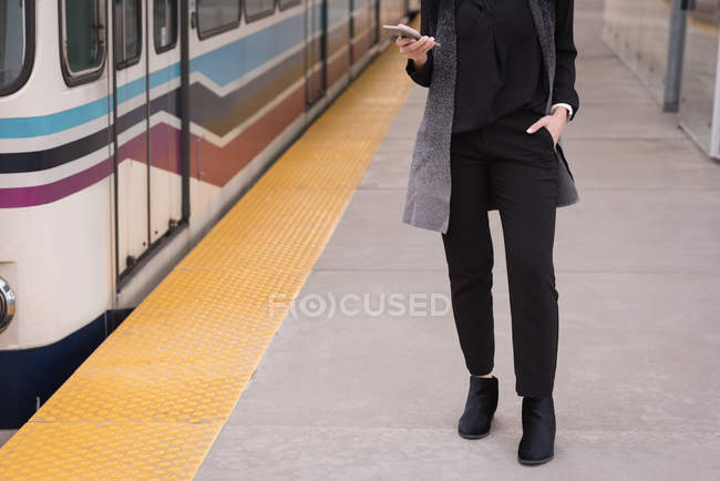 Woman using mobile phone at railway station — Stock Photo