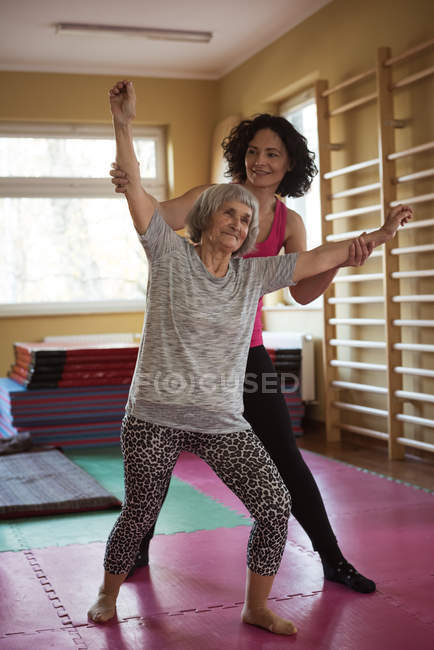 Female therapist assisting senior woman with hand exercise at nursing home — Stock Photo