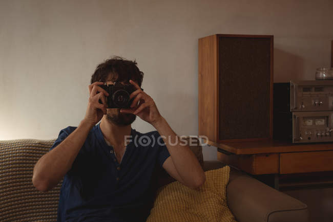 Uomo scattare foto con fotocamera vintage in soggiorno a casa — Foto stock