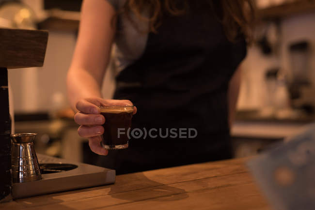 Partie médiane du barista femelle servant du café au comptoir dans le café — Photo de stock