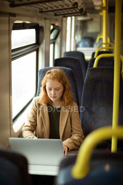 Cabelo vermelho jovem mulher usando seu laptop no trem — Fotografia de Stock