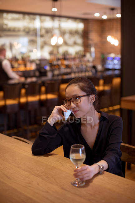 Mulher falando no celular enquanto bebe vinho no hotel — Fotografia de Stock