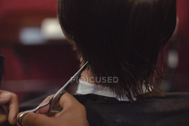Hombre recibiendo su pelo recortado con tijera en la barbería - foto de stock