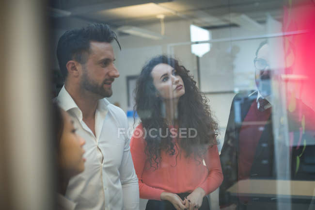 Business executives looking at sticky notes in office — Stock Photo