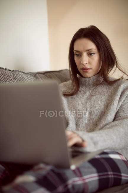 Frau benutzt Laptop auf Sofa im heimischen Wohnzimmer. — Stockfoto
