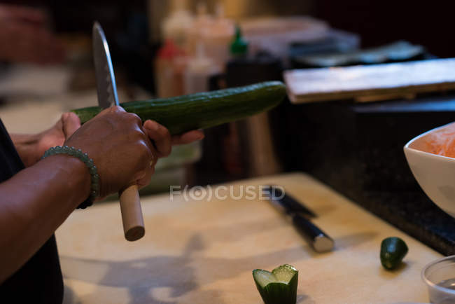 Chef slicing cucumber with a deba knife in kitchen restaurant — Stock Photo