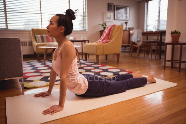 Mulher realizando ioga na sala de estar em casa — Fotografia de Stock