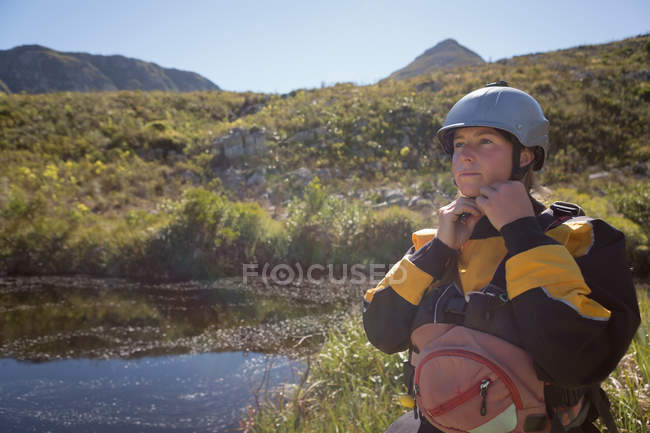 Woman wearing helmet by river in mountains. — Stock Photo