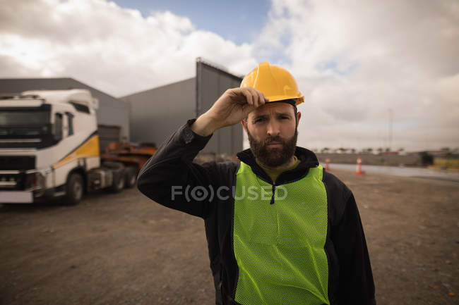 Portrait of dock worker holding his hat in shipyard — Stock Photo