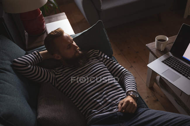 Мужчина лежит на диване и смотрит ноутбук дома — стоковое фото