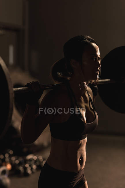 Fit woman exercising with barbell in the studio — Stock Photo