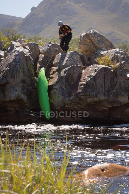 Woman pulling kayak boat on rocks by river. — Stock Photo