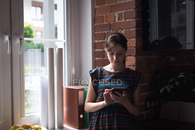 Femme cadre utilisant le téléphone portable dans le bureau — Photo de stock