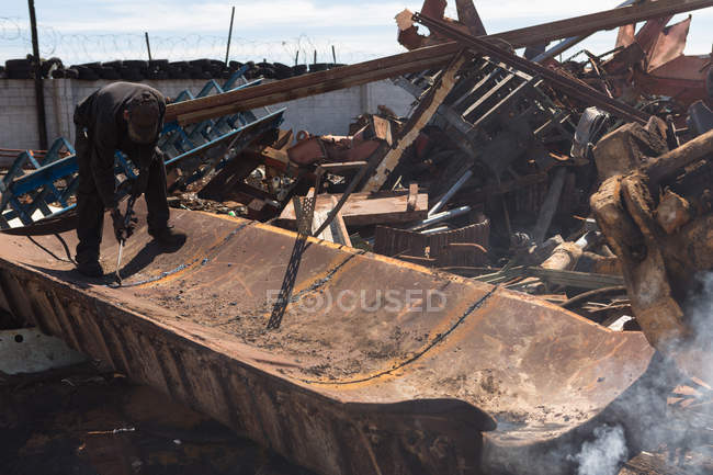 Worker working on metal scrap in scrapyard — Stock Photo