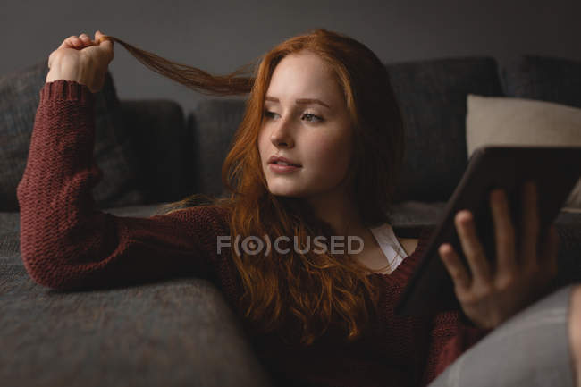 Thoughtful woman using digital tablet at home — Stock Photo