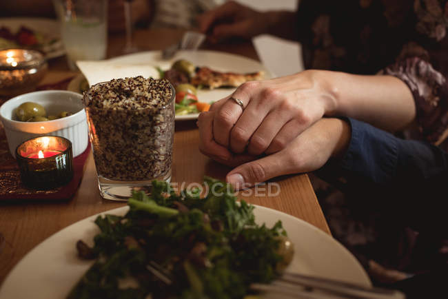 Coppia che si tiene per mano mentre pranza a tavola — Foto stock