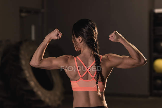 Rear view of fit woman flexing her muscles in the fitness studio — Stock Photo