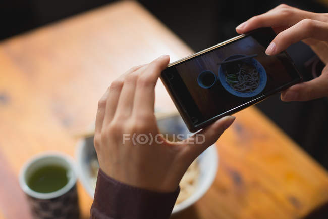 Woman taking photo of meal with mobile phone in restaurant — Stock Photo