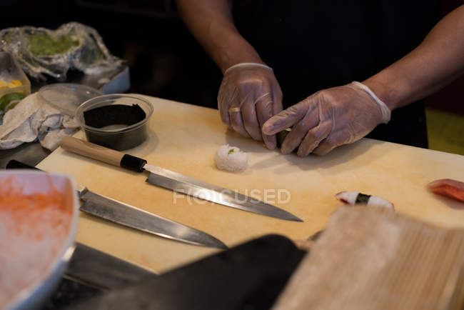 Chef rodando sushi desenrollado en una cocina de restaurante - foto de stock