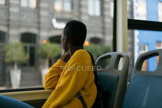 Giovane donna che guarda attraverso la finestra mentre viaggia in autobus — Foto stock