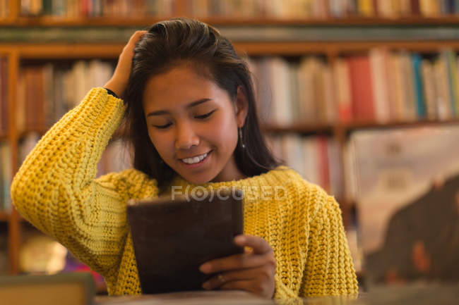Adolescente utilisant une tablette numérique dans la bibliothèque — Photo de stock
