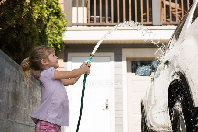 Девушка моет машину в гараже в солнечный день — стоковое фото