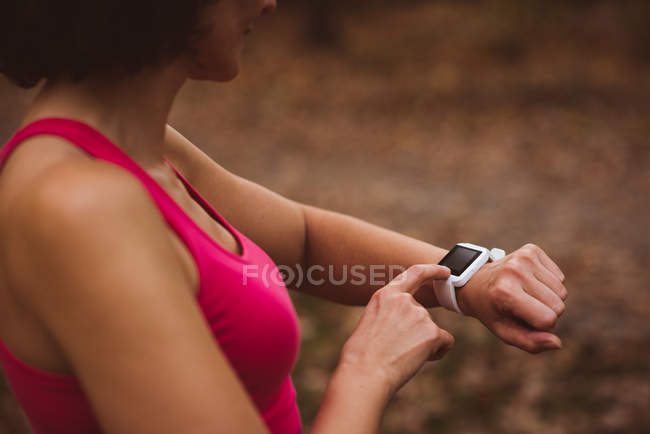 Женщина среднего звена использует умные часы в лесу — стоковое фото