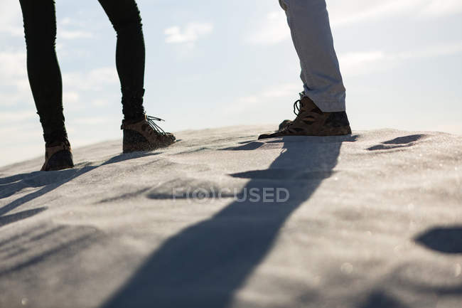 Низкая часть пары, стоящей на песке — стоковое фото