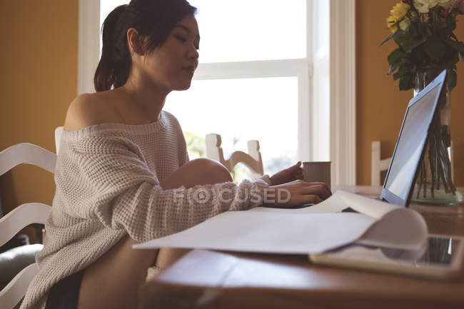 Jeune femme utilisant un ordinateur portable à la maison — Photo de stock